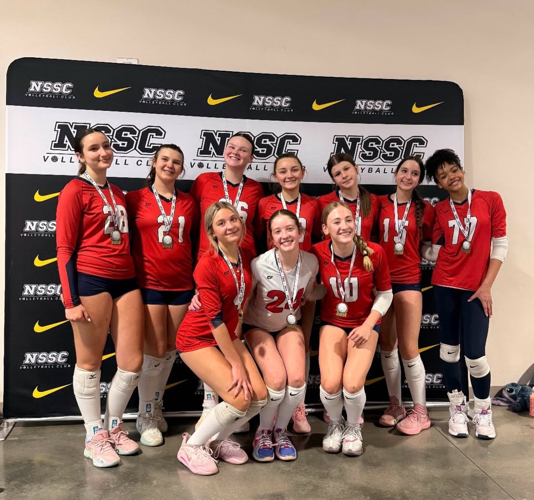 Nine 314 VBC players in red jerseys wearing silver medals in front of an NSSC Volleyball Club step-and-repeat banner.