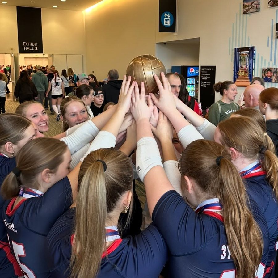 314 Volleyball Club players in a huddle with their hands stacked on a ball before a match